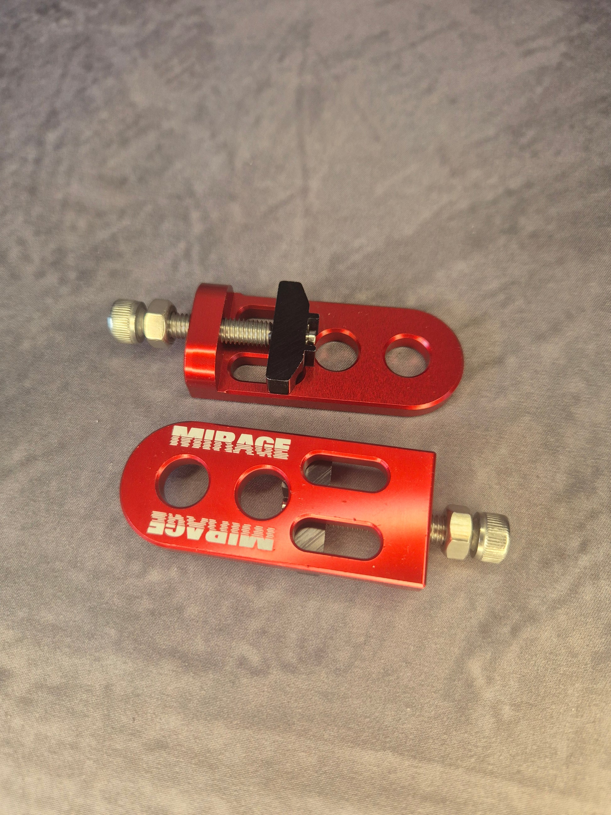 Two red metal BMX chain tensioner components with 'Mirage' branding on a grey background